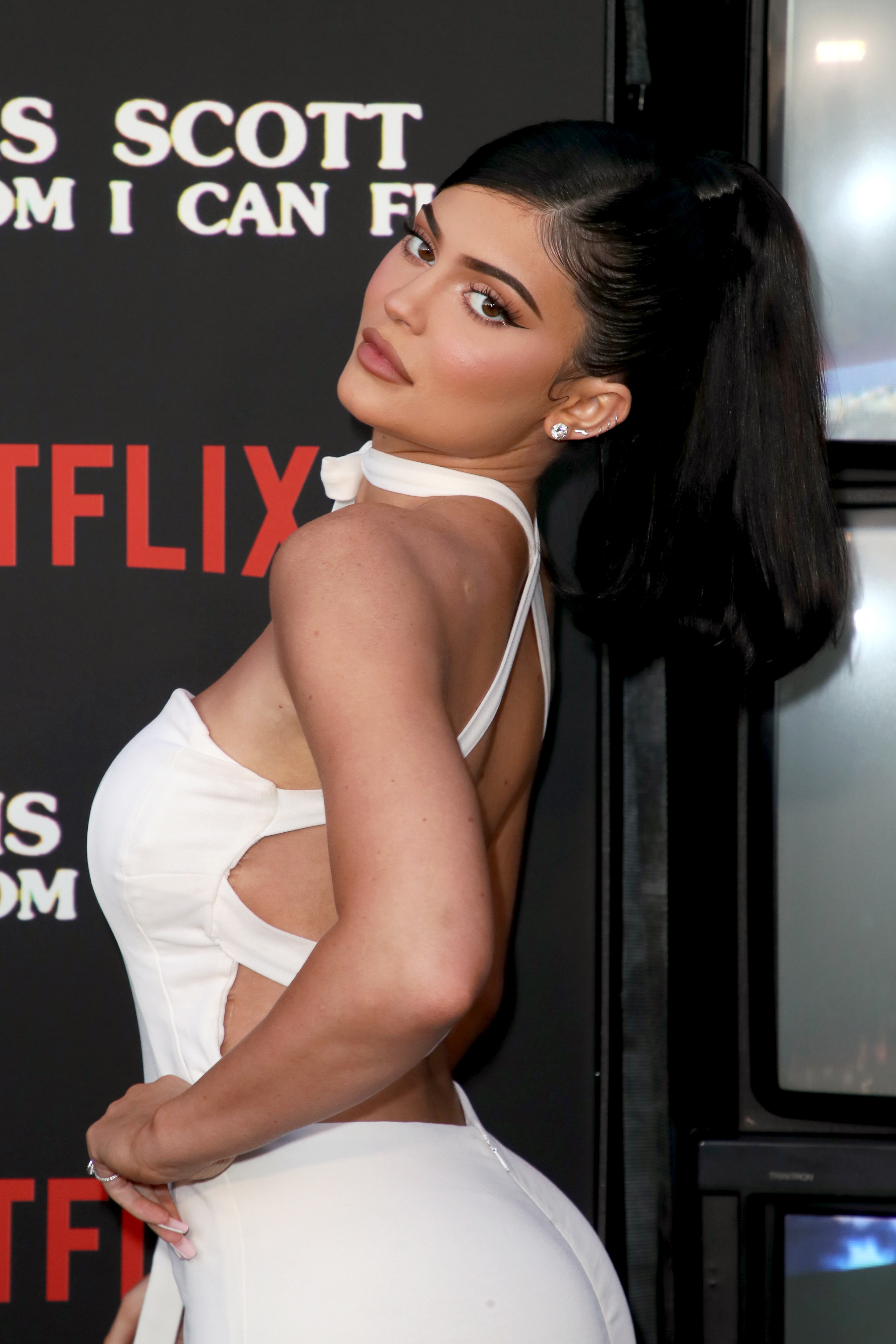 Kylie Jenner poses side-on in a dress with a high ponytail at an event