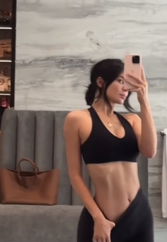 kylie pulling down her waistband to reveal her stomach after a workout