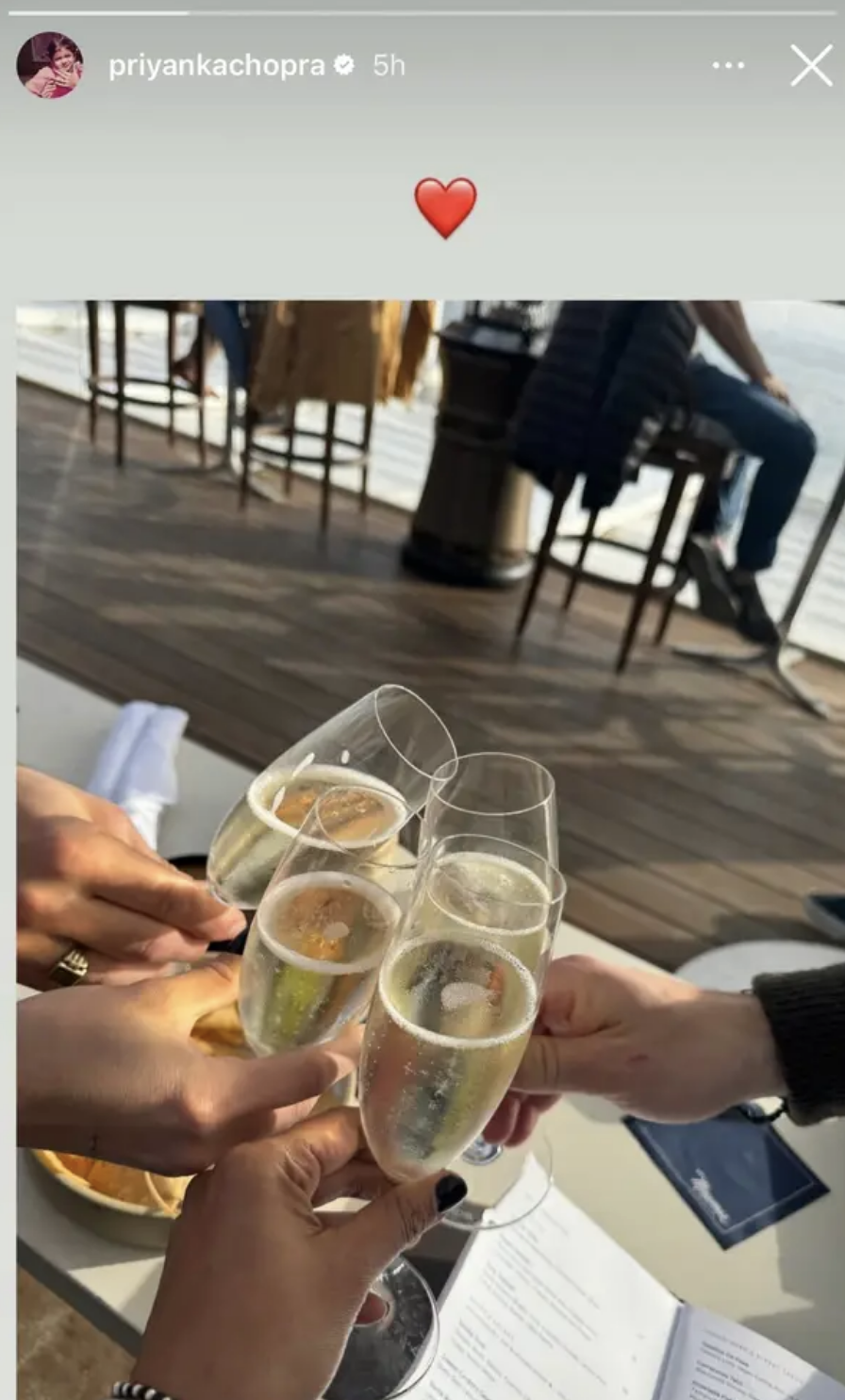 Three people toasting with champagne flutes over a wooden table with a blurred background