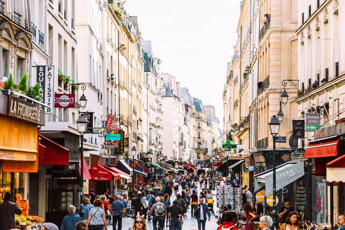 Crowded street in European city with pedestrians and various shops