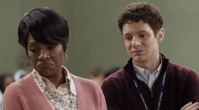 Two actors portraying frustration, woman with folded arms and a skeptical look, man looking down. Characters from a TV show or film