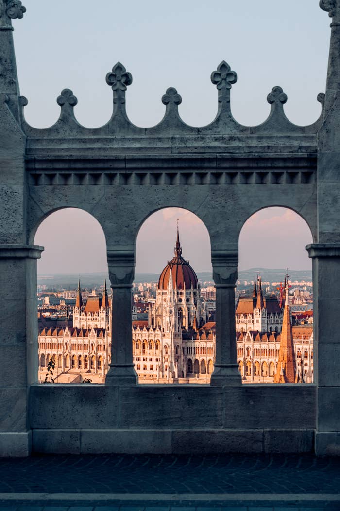 View of a historic building through arched stone window, at dusk