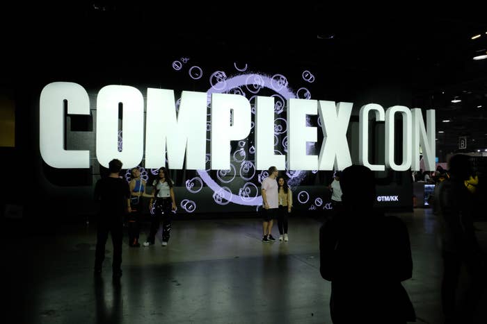 Attendees in front of a lit &#x27;COMPLEXCON&#x27; sign at a music event