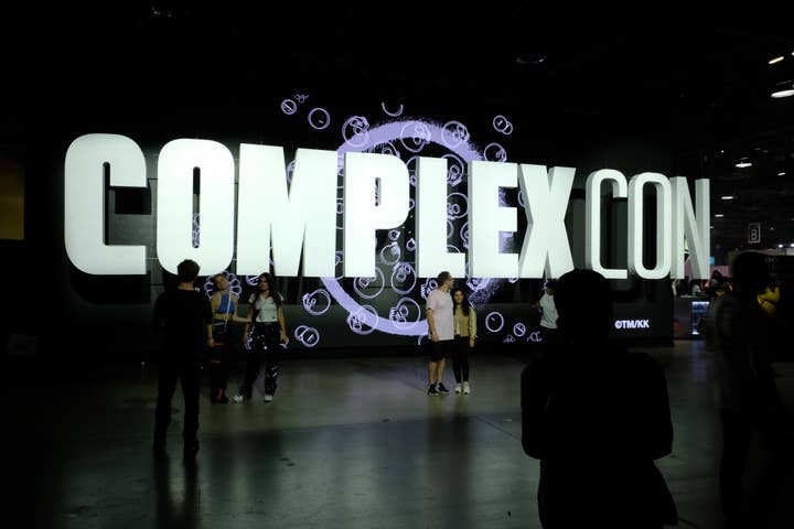 Attendees in front of a lit 'COMPLEXCON' sign at a music event