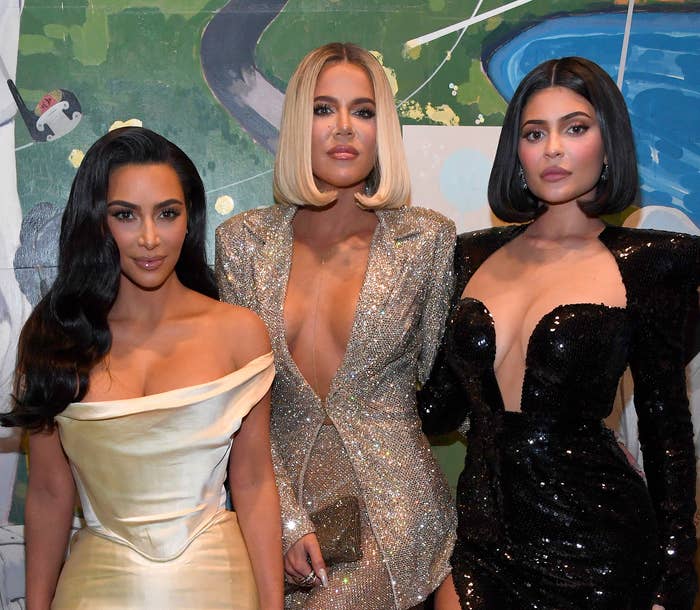 Kim Kardashian in a satin gown, Khloé Kardashian in a glittery dress, and Kylie Jenner in a sequined outfit standing together
