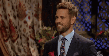 Nick from the &quot;Bachelor&quot; with a rose in hand, smiling and nodding in an animated manner