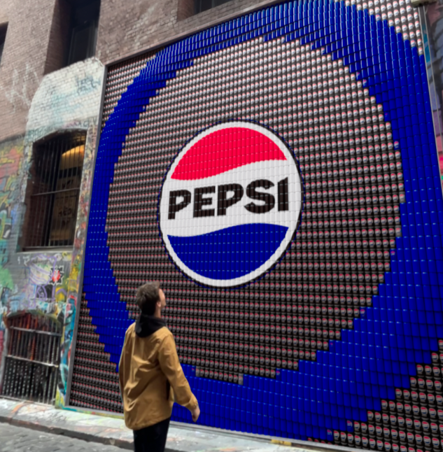 Person standing before a large Pepsi logo mural on an urban building wall