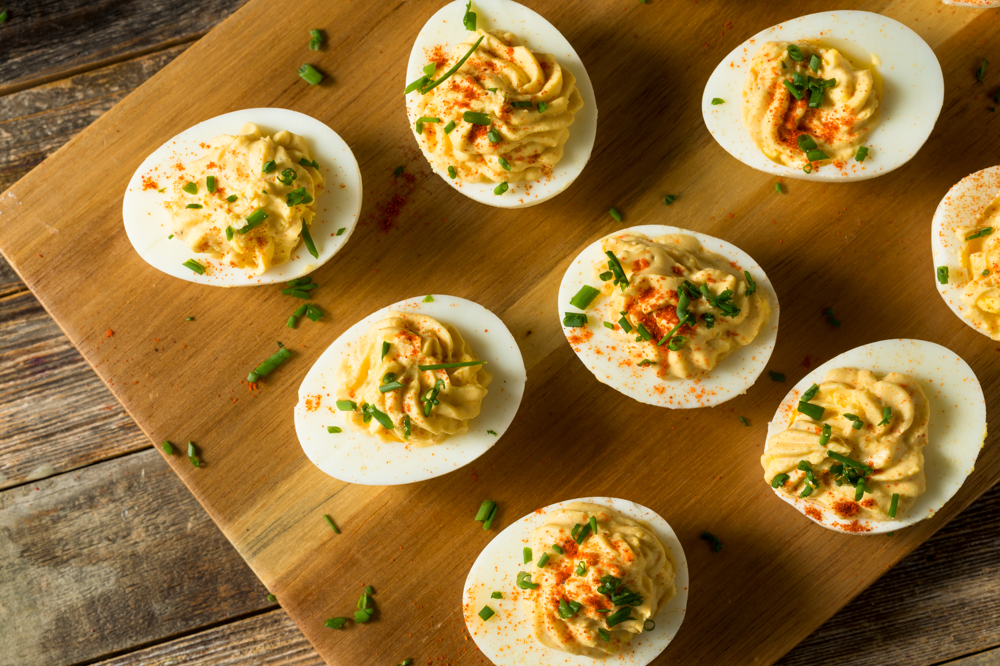 Deviled eggs on a wooden board garnished with paprika and herbs