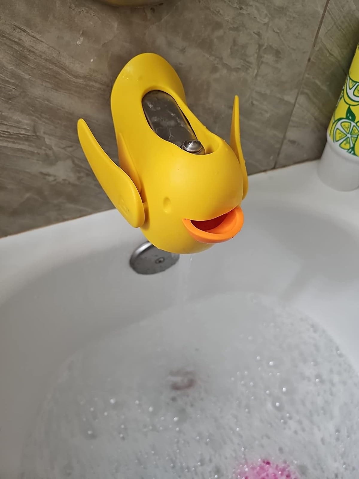 Yellow duck-shaped faucet cover on a bathtub spout