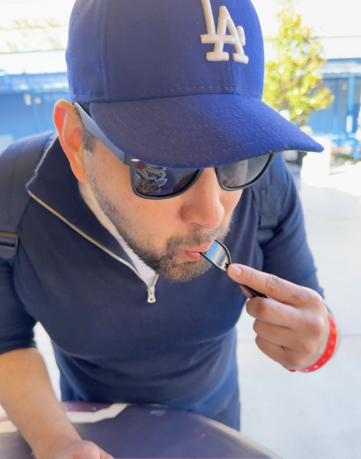 Man in baseball cap using a whistle, outdoors, possibly at a sports or travel event