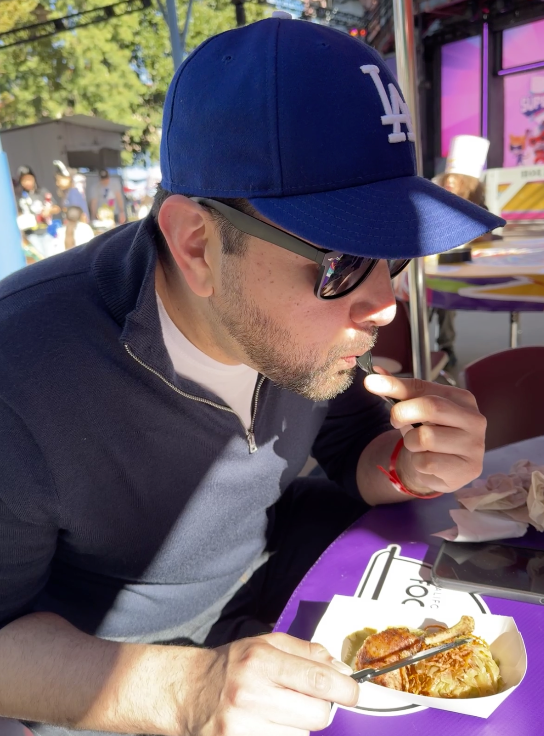 Man tasting food at an outdoor market, capturing a travel dining experience