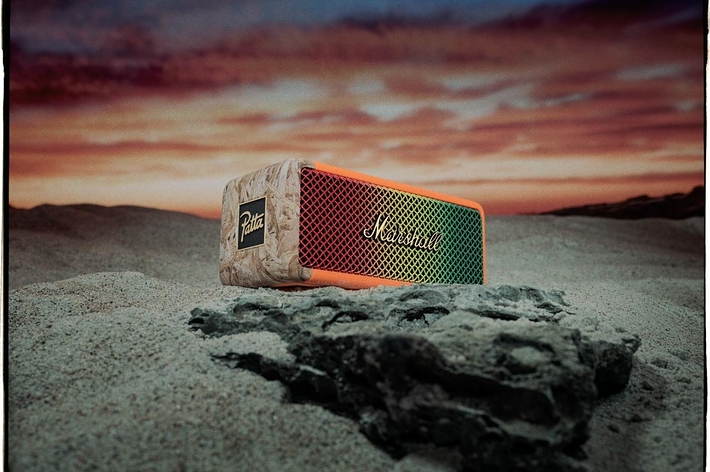 Marshall portable speaker on sand with a sunset backdrop