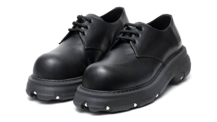A pair of black leather derby shoes with thick soles on a white background