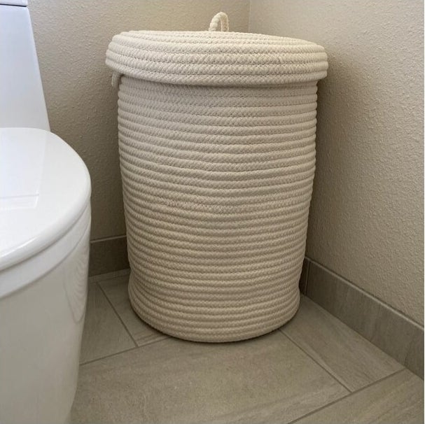 A white rope-style laundry basket with lid,