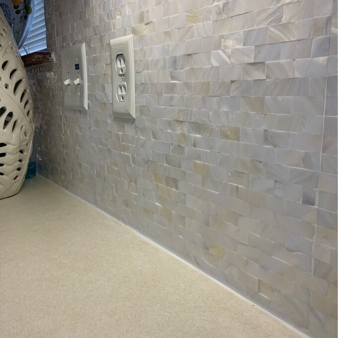 the mother of pearl tiles on a wall around an electrical outlet