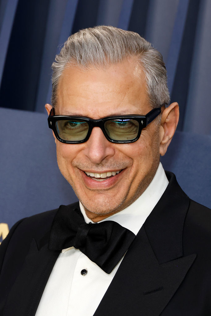 Jeff Goldblum in a tuxedo with a bow tie, smiling, wearing sunglasses