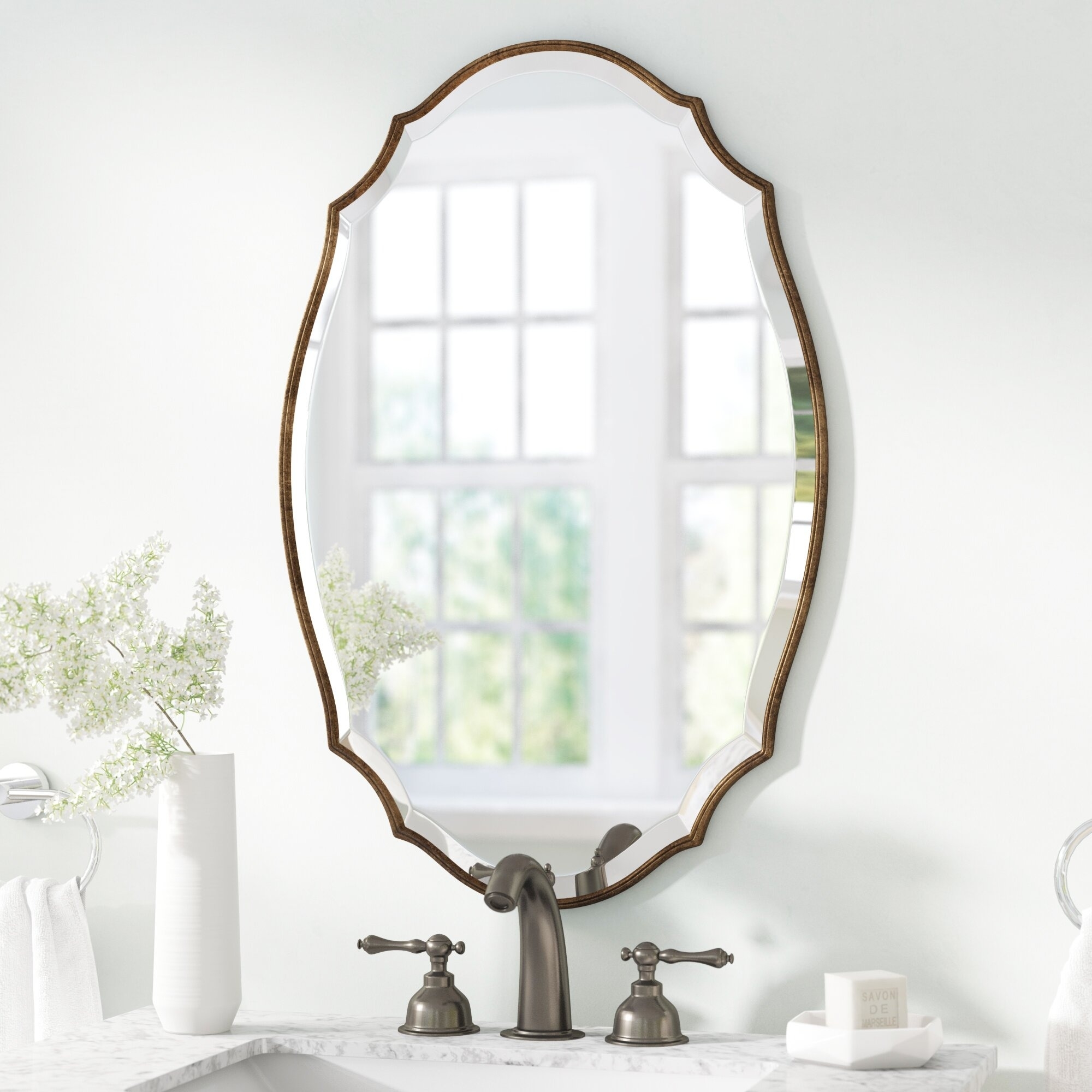 Elegant wall mirror with a unique frame design displayed above a bathroom sink