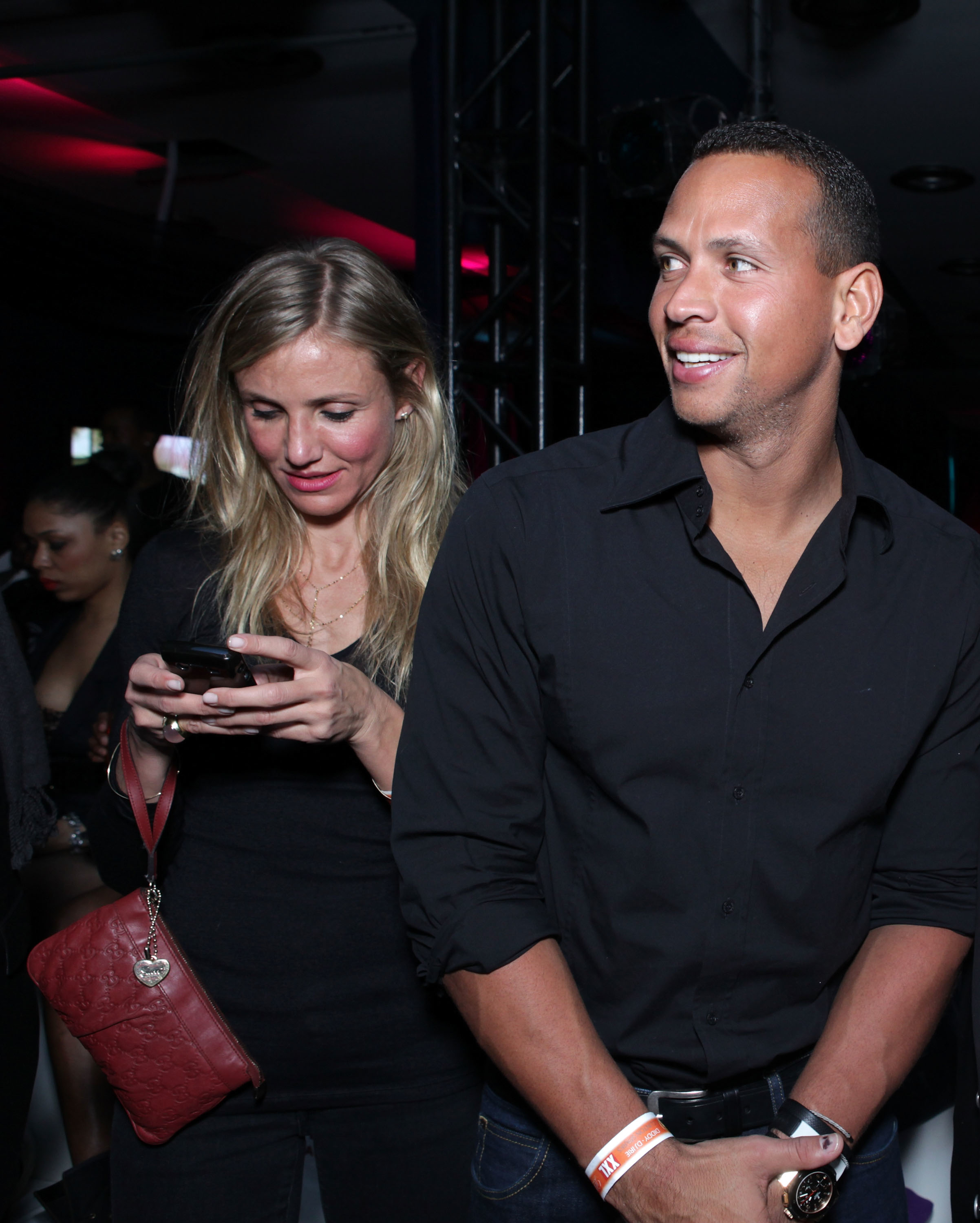 Cameron using a phone and standing next to A-Rod, both casually dressed