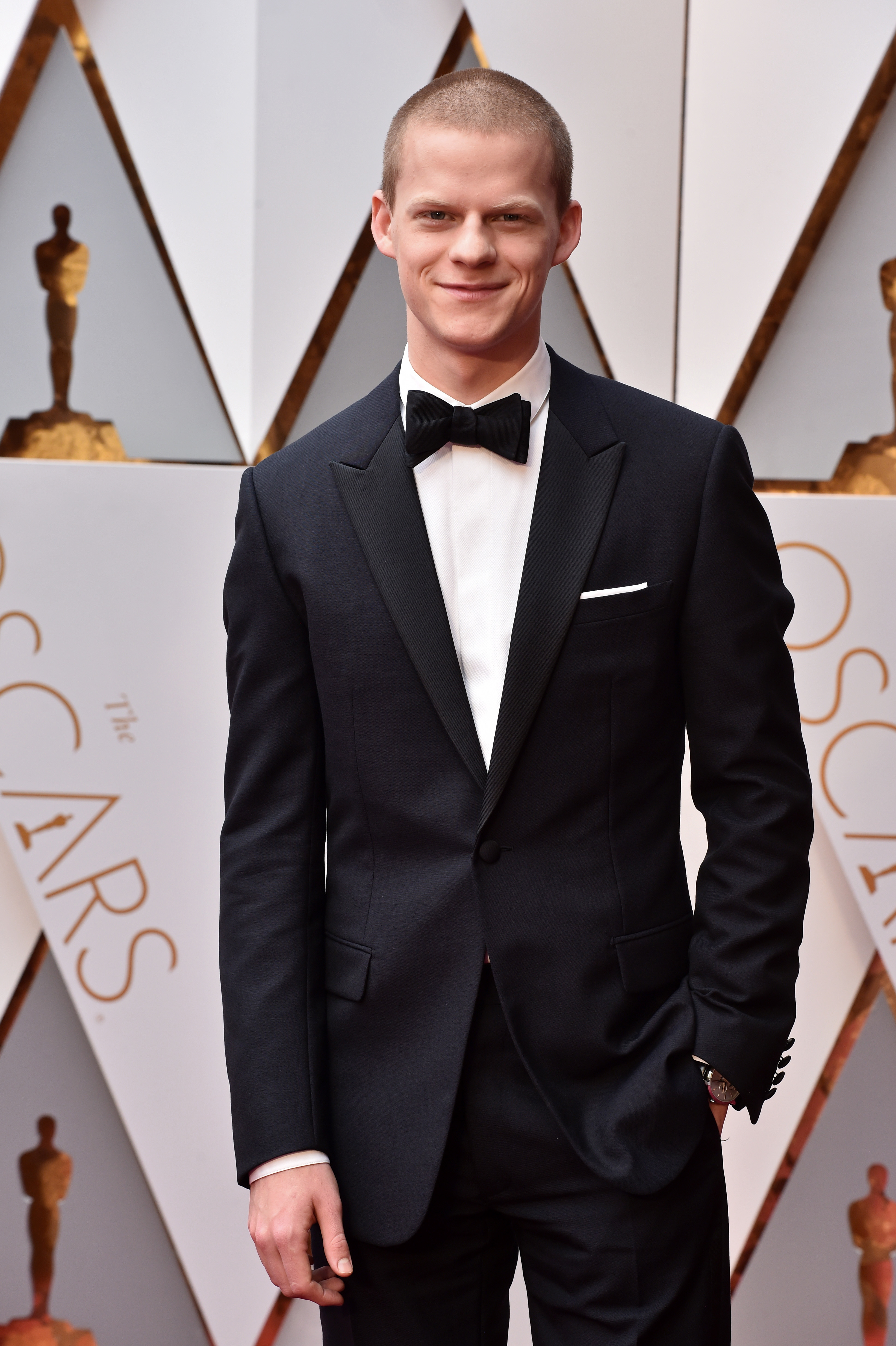 Lucas Hedges in a classic black tuxedo with a bow tie on the Oscars red carpet