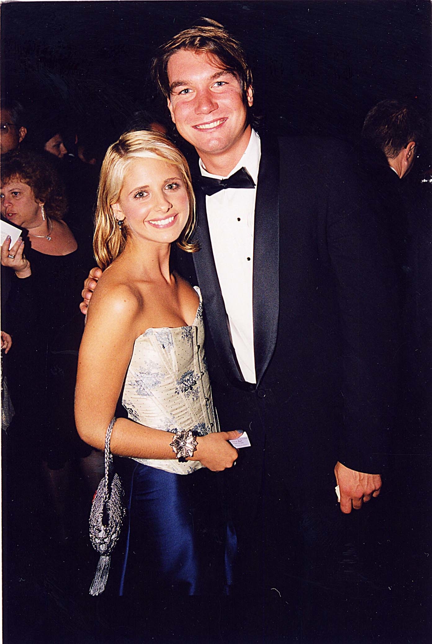 Sarah smiling in a strapless dress with embellishments, Jerry smiling in a classic tuxedo