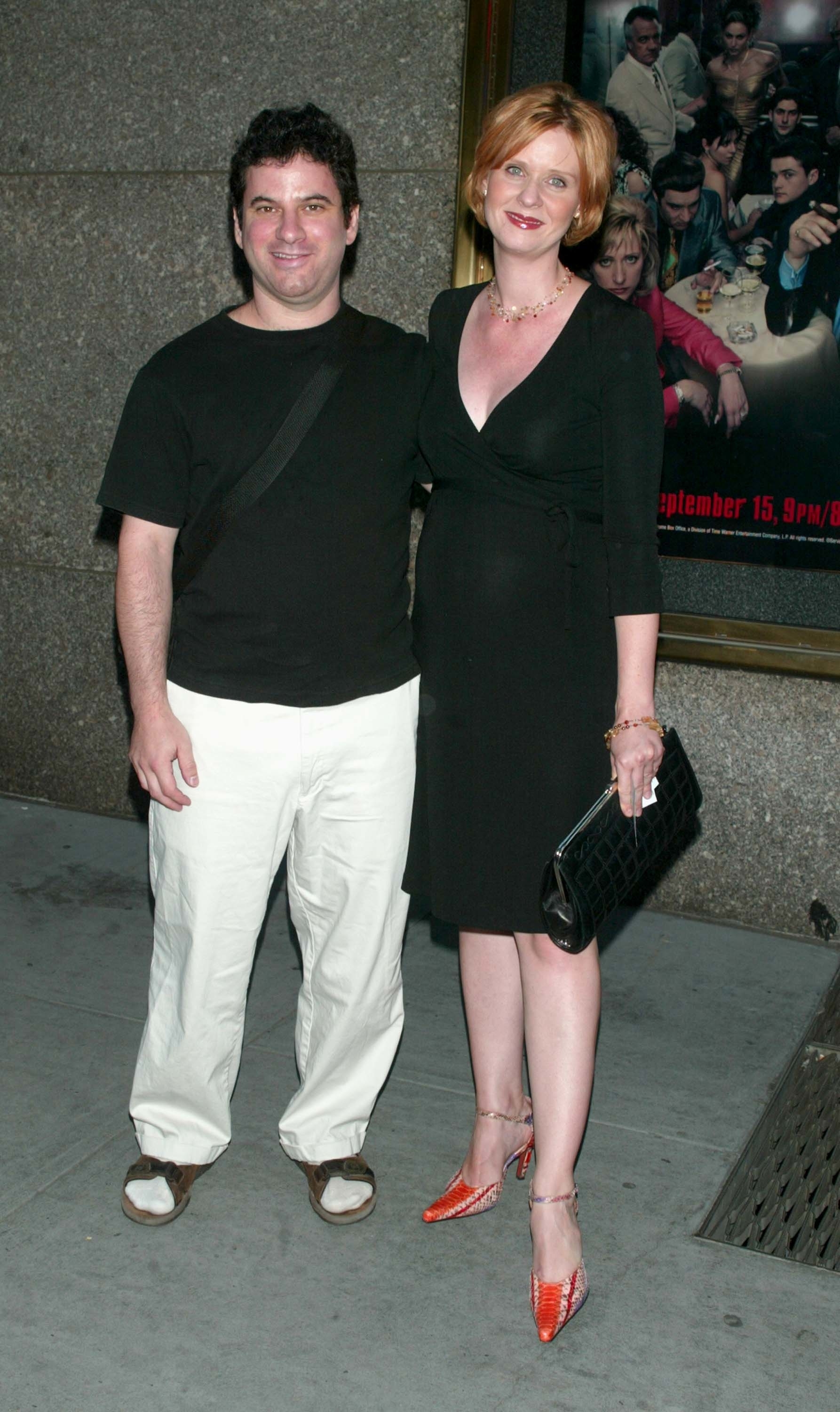 Danny in a black top and white pants, and Cynthia in a black dress with a V-neckline and orange shoes