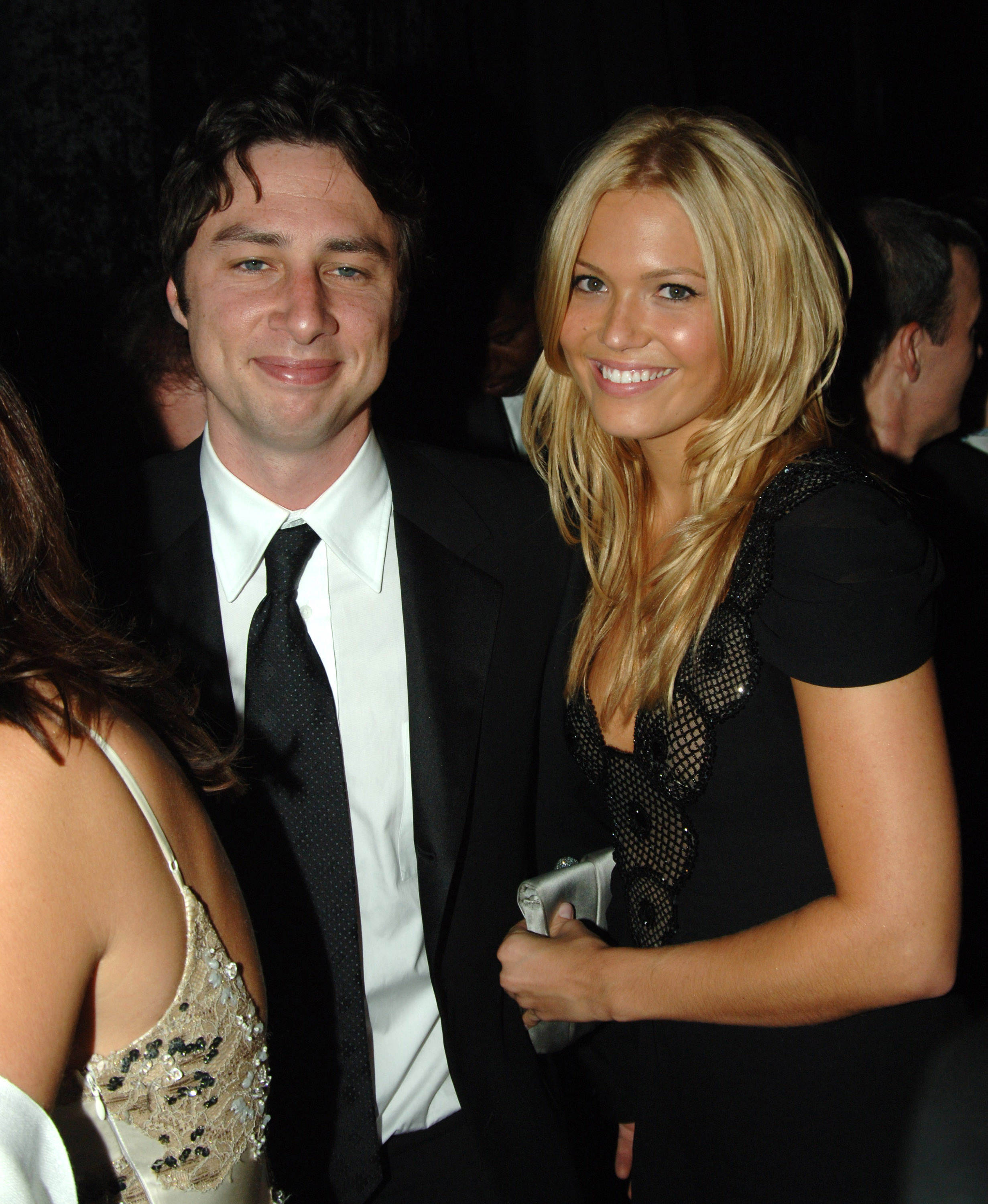 Zach in a suit and tie next to Mandy in a black dress with unique neckline at event