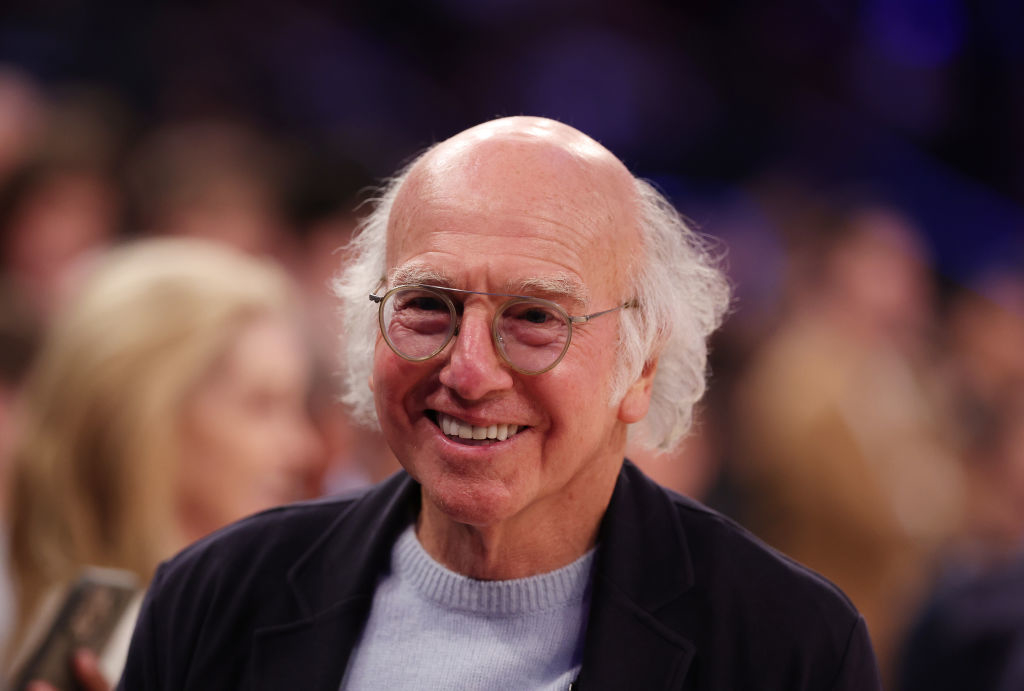 Smiling elderly man with glasses, wearing a blazer over a shirt