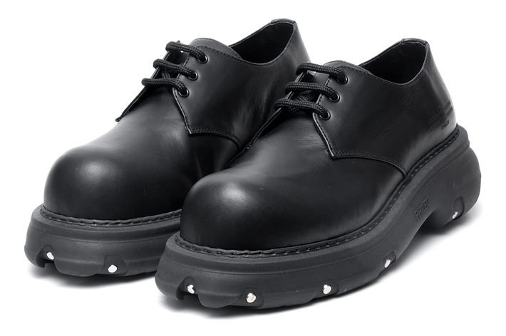 A pair of black leather derby shoes with thick soles on a white background