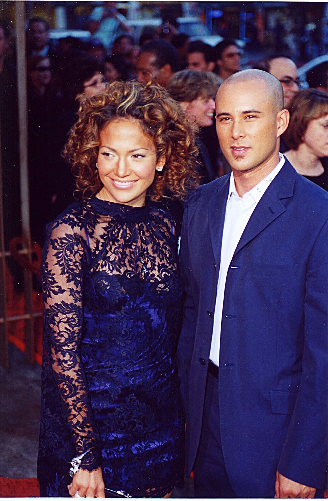 On the red carpet: JLo with curly hair and wearing a lace dress, Chris in a suit