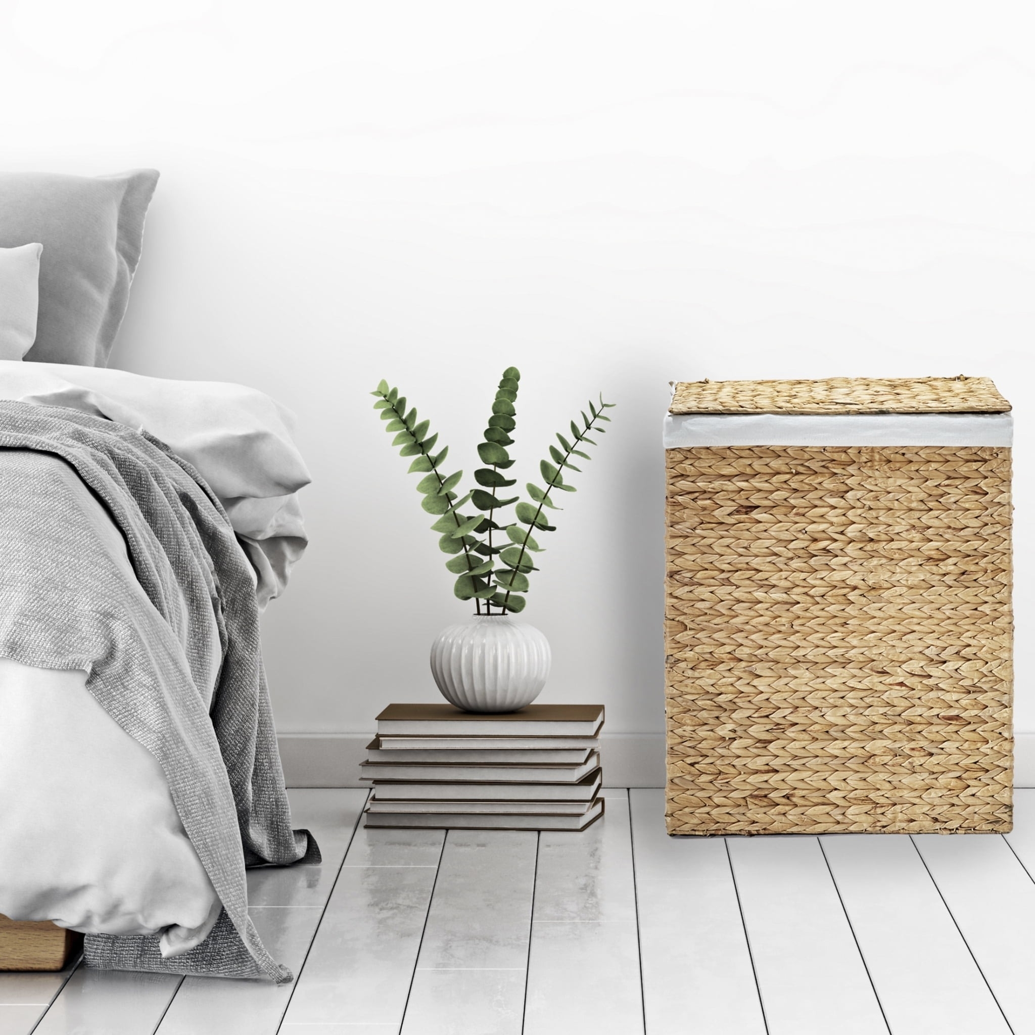 Bed with gray blankets, a woven hamper basket, and a plant on stacked books next to the bed for home decor inspiration