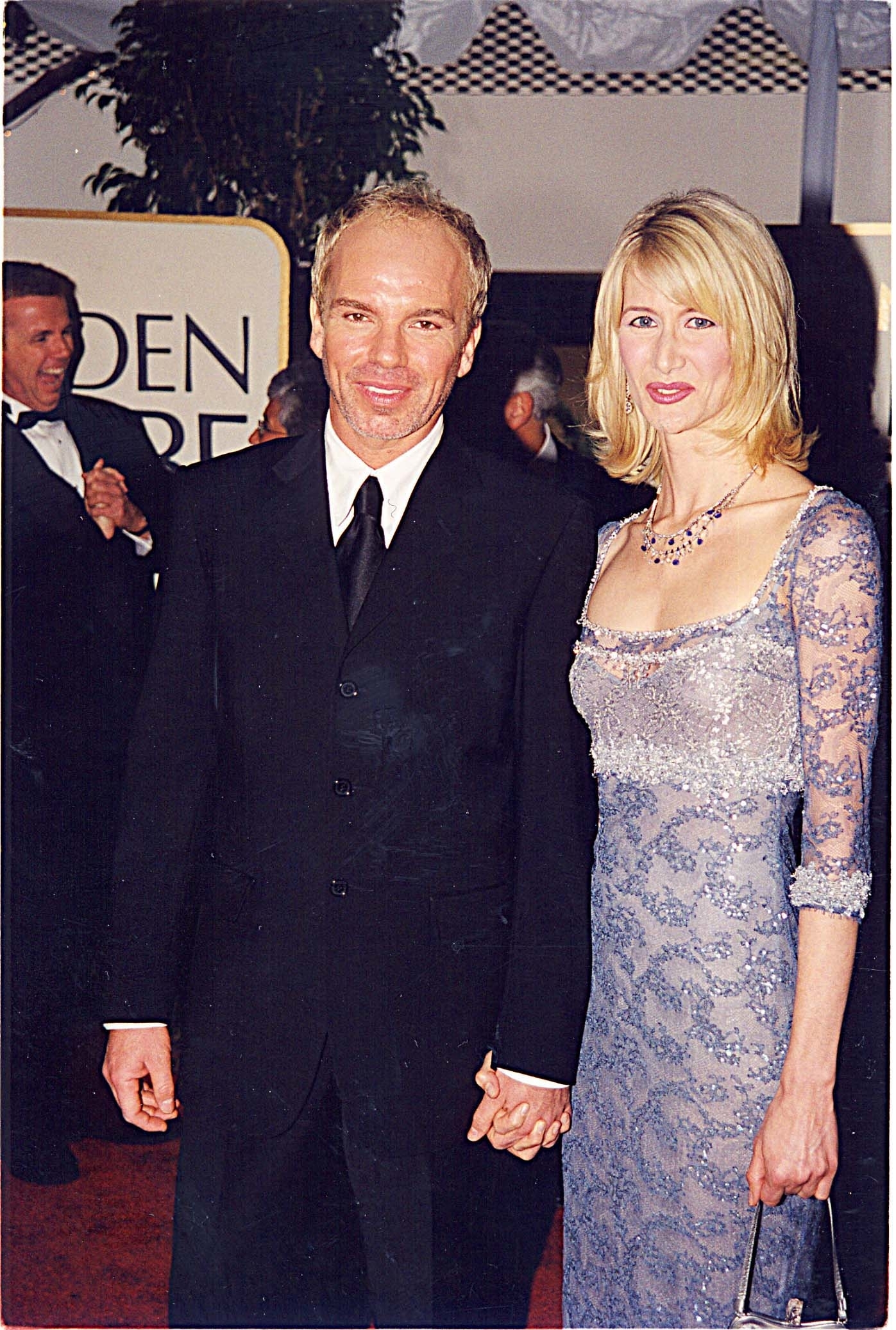 Billy Bob in a black suit and Laura in a beaded lace dress, holding hands on the red carpet