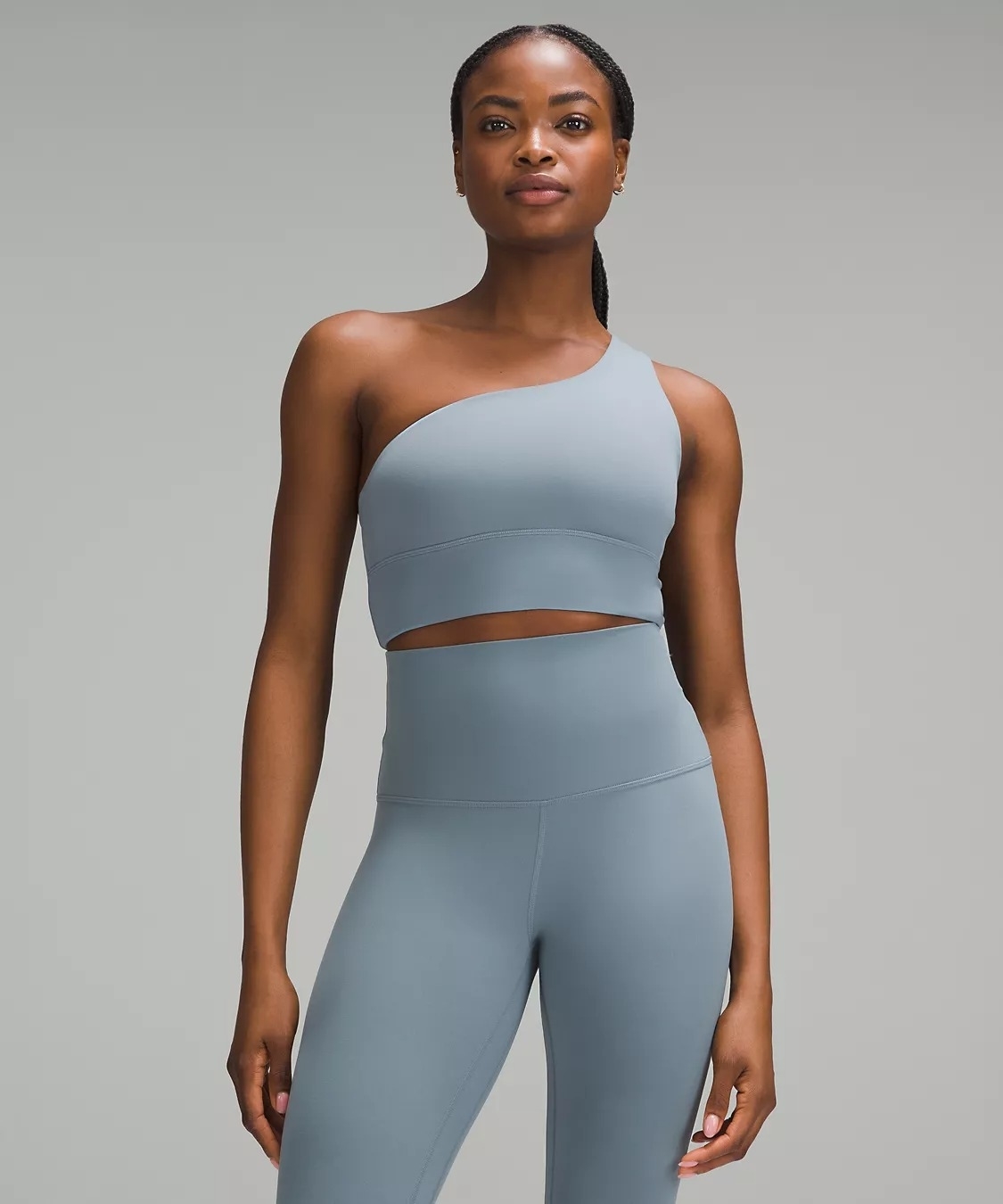 Model in a blue one-shoulder sports bra and matching leggings