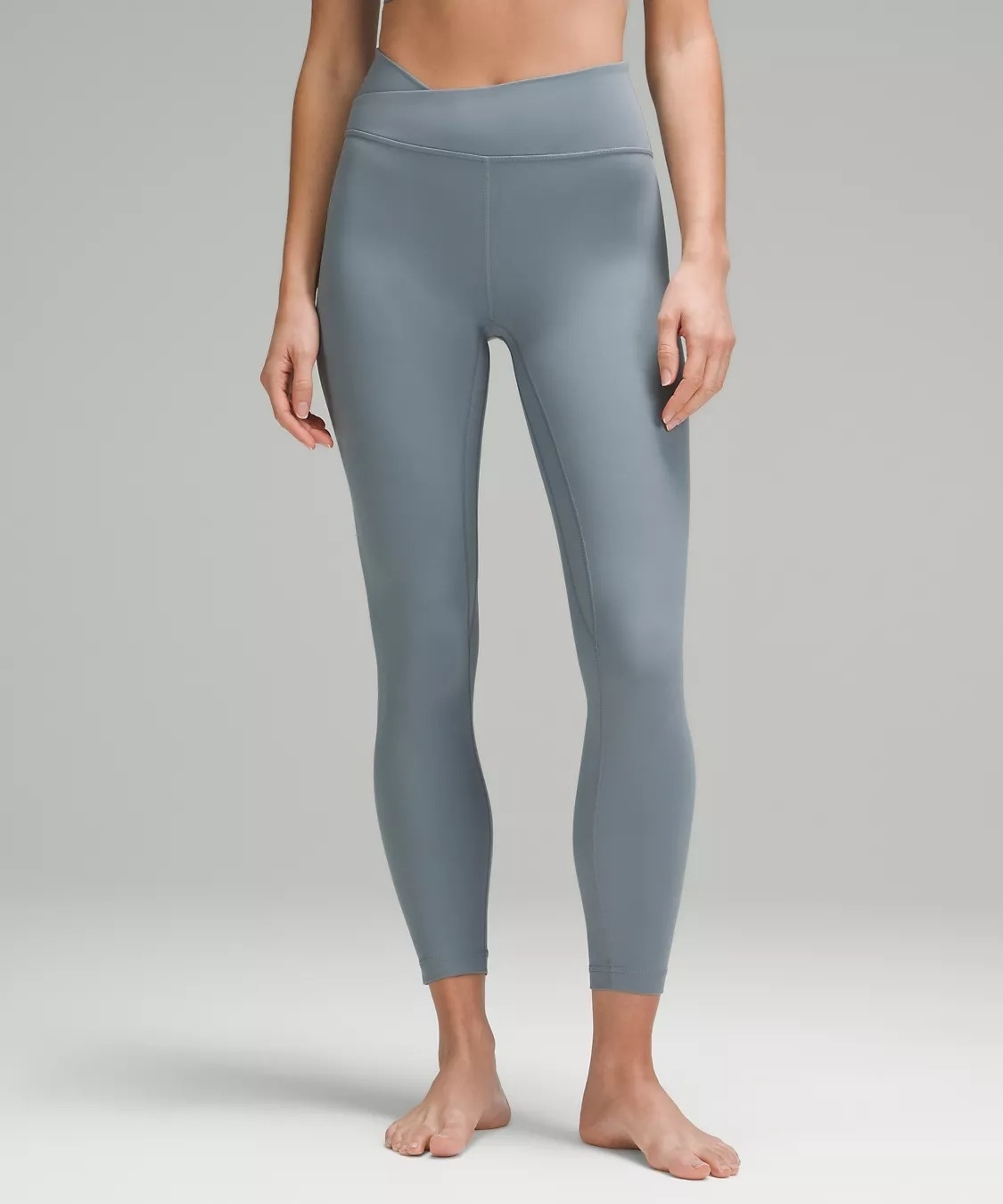 model wearing gray ankle-length leggings with asymmetrical waist band design