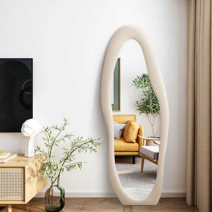 Elliptical wall mirror in a living room with a mustard armchair and decorative plants