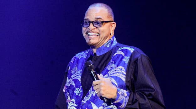 Sinbad wearing a patterned shirt and blazer, performing stand-up comedy with a microphone