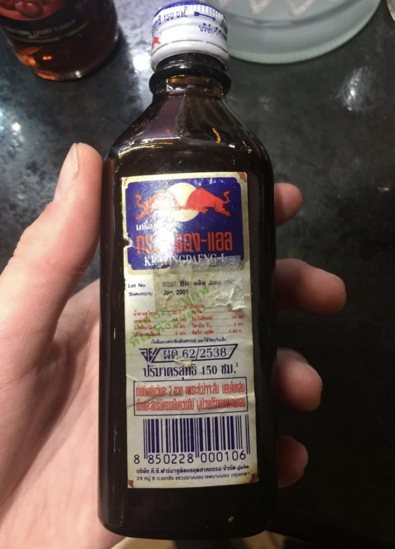 Hand holding a bottle that looks like medicine with Thai text
