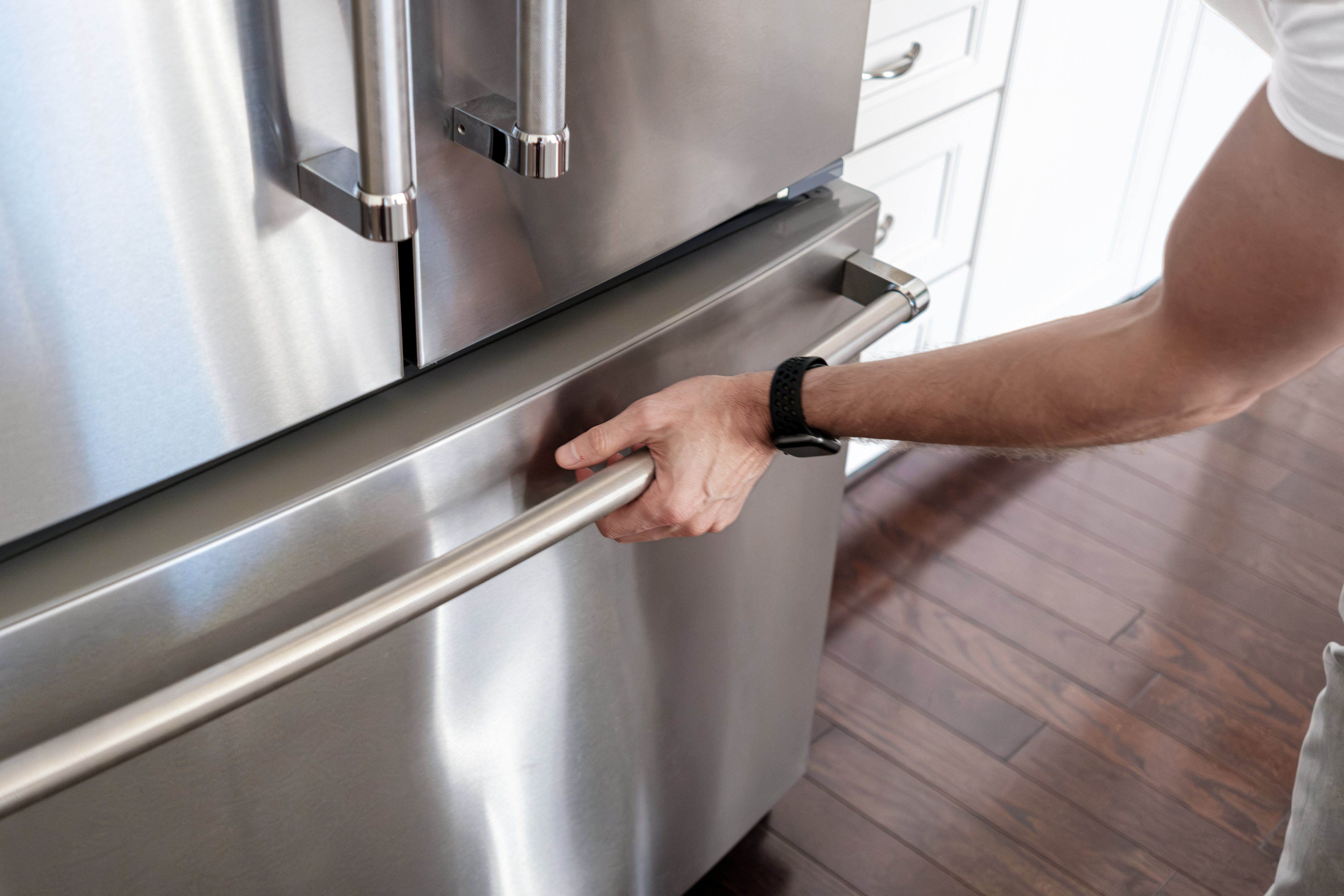 Person opening a stainless steel refrigerator door