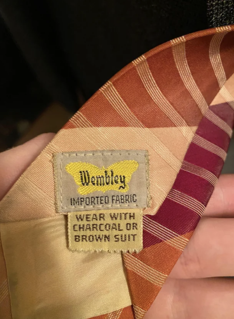 Close-up of a Wembley tie label suggesting to &quot;wear with charcoal or brown suit.&quot;
