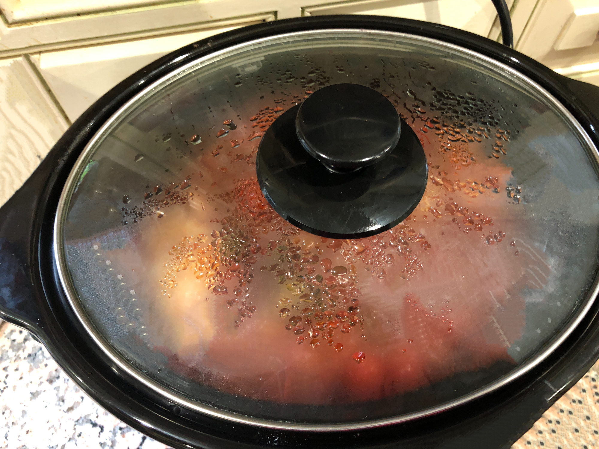 Food cooking in a closed slow cooker on a kitchen countertop