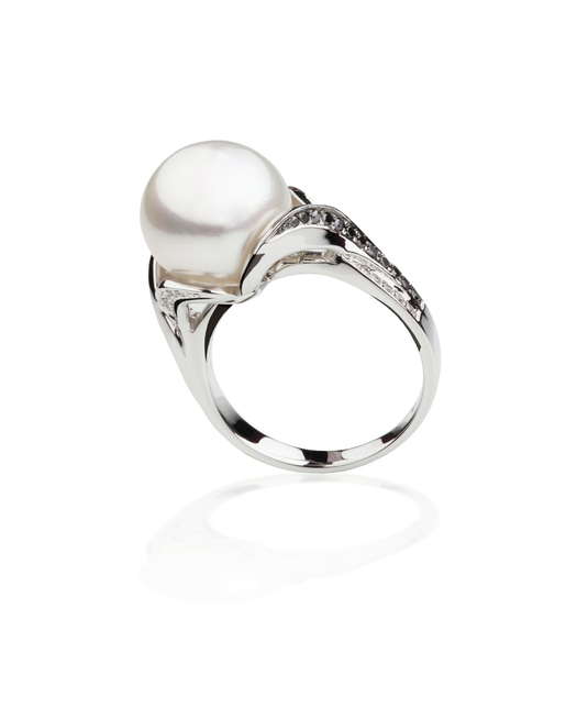 Pearl ring with diamond accents on a reflective surface