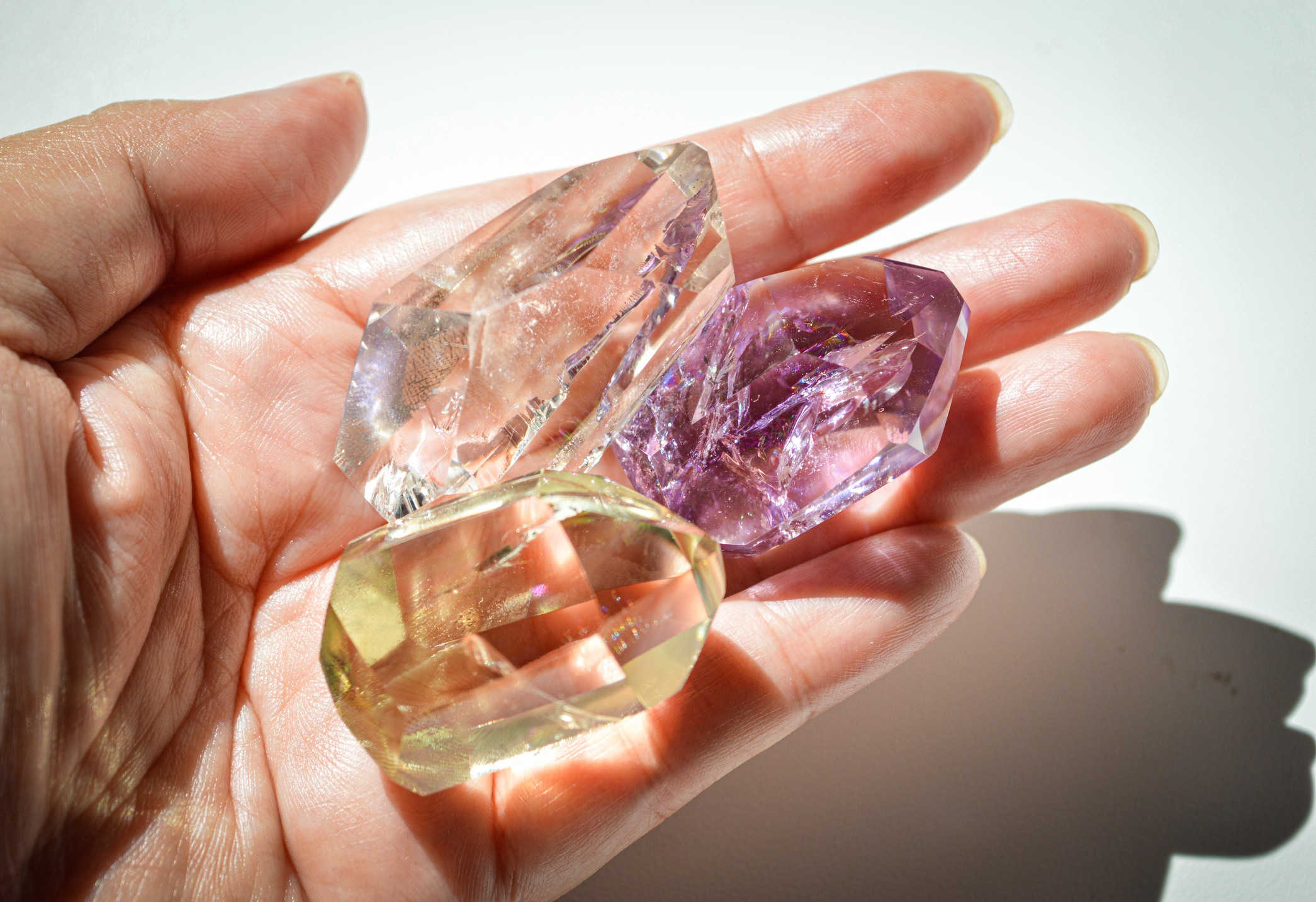 Hand holding three translucent crystals of varying shapes and sizes without any discernible text or individuals to name
