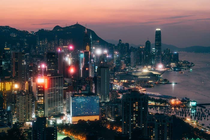 A twilight cityscape showing the illuminated skyline and waterfront of Hong Kong