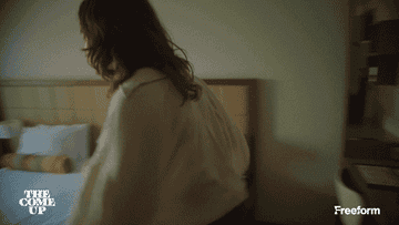 Person in a casual shirt and jeans jumps laying onto a bed