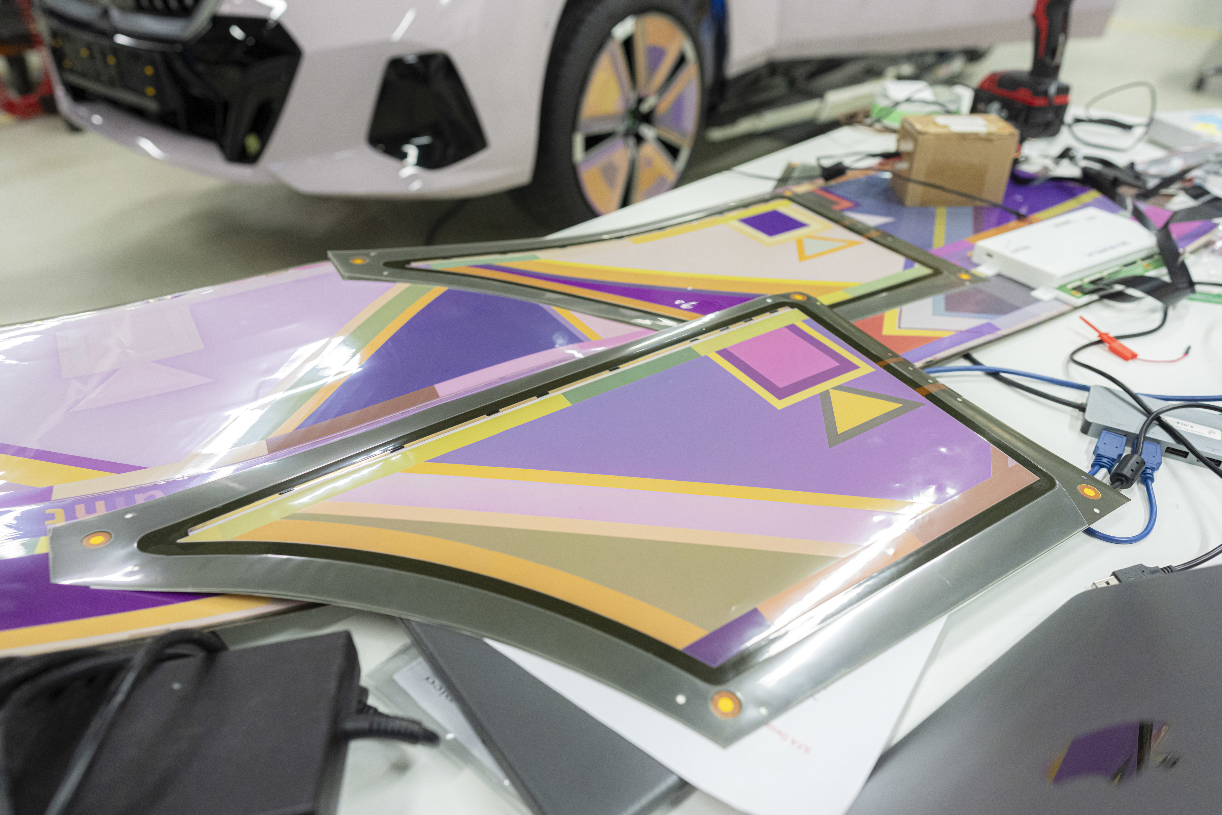 Car wraps with geometric patterns laid out for application, work equipment in background