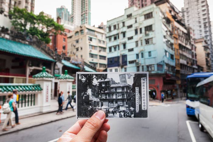 Hand holding a black and white photo aligned with Hong Kong background to compare past and present architecture