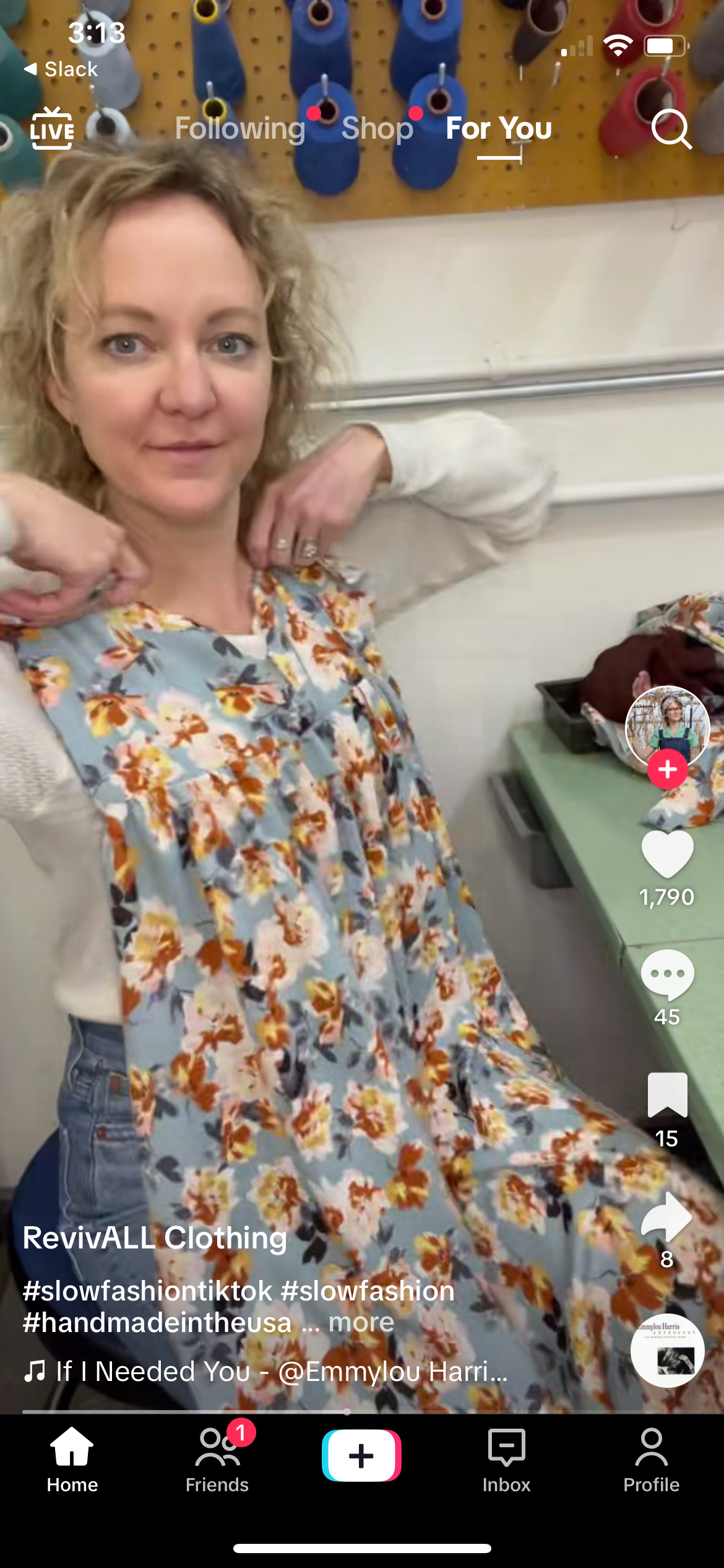 Woman presenting a floral dress amid a fabric-filled background