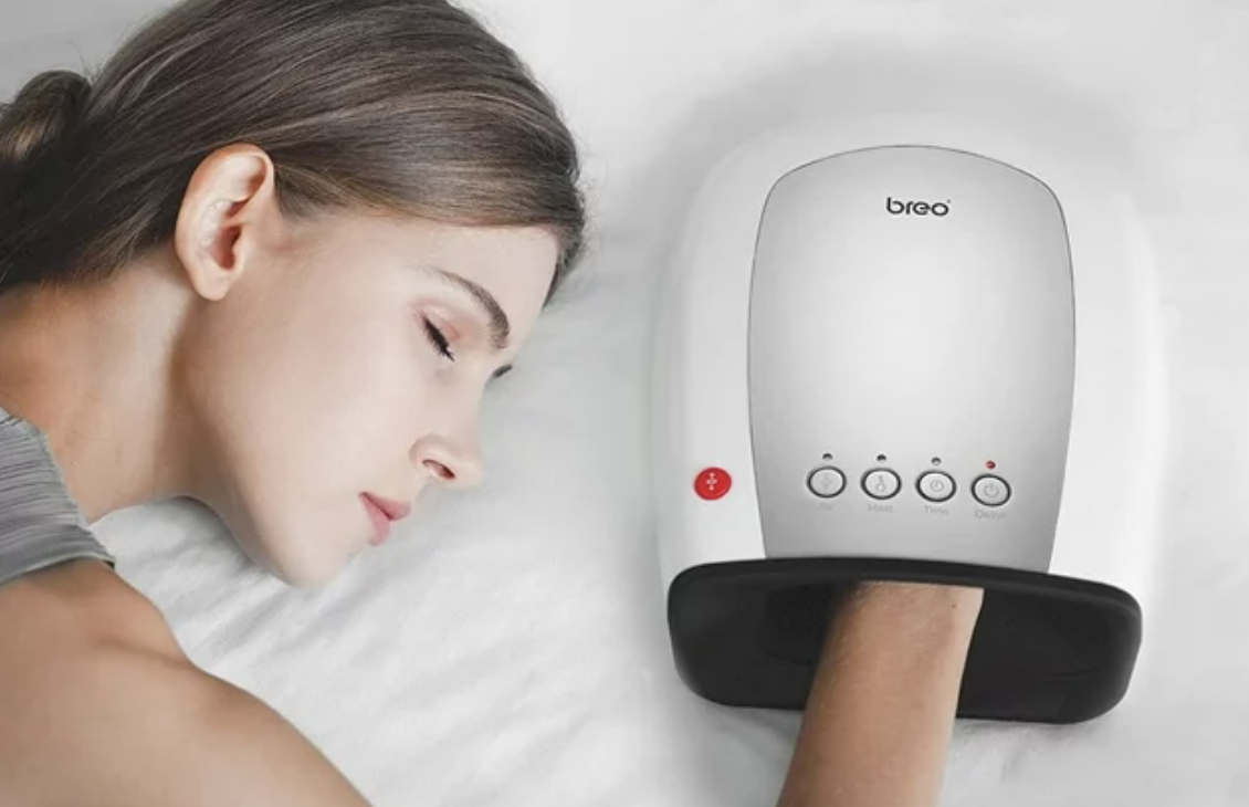 Person resting with a hand massager on pillow for relaxation