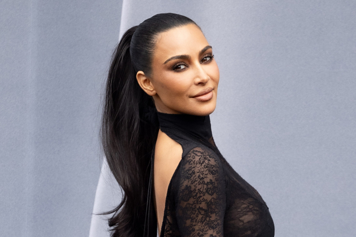 Kim Kardashian posing in a black lace outfit with a high collar