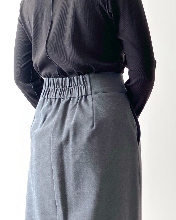 後ろ姿の人がブラウスとスカートのファッションをしています。