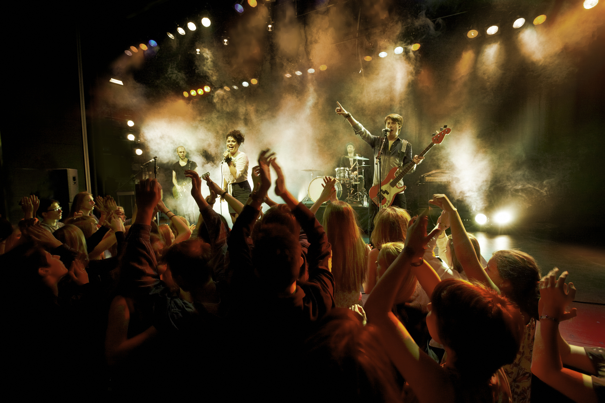 A band performs on stage in front of an enthusiastic crowd at a concert venue